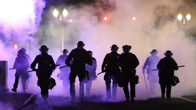 Police officers walk enveloped by teargas in Portland. Picture: Dave Killen