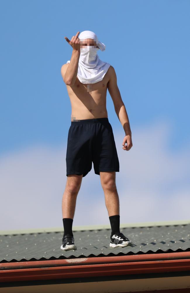 The youth made obscene gestures and shouted at the media as authorities worked to get him down from the roof. Picture: Alex Coppel