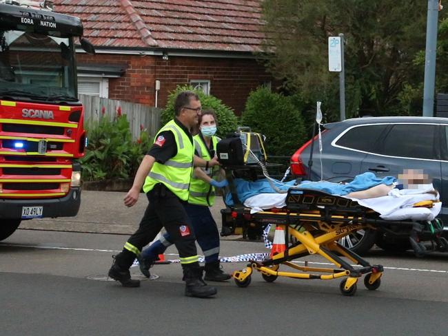 Paramedics move one of the injured on a stretcher on West St, Cammeray. Picture: OnScene Bondi