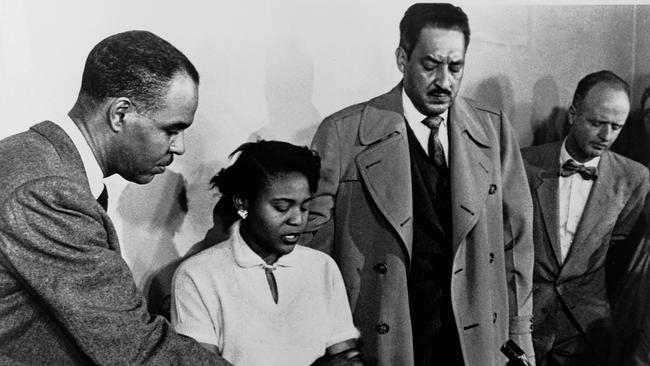 Roy Wilkins, Director of the National Association for the Advancement of Colored People, holds a piece of paper for Autherine Lucy as she speaks at a press conference along with Thurgood Marshall.