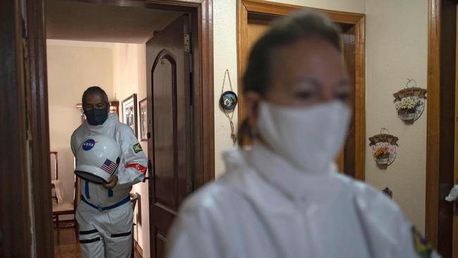 Brazilian accountant Tercio Galdino, 66, and his wife Alice Galdino leave their apartment to go to Copacabana beach in protective suits to protect themselves from the virus. Picture: AFP.