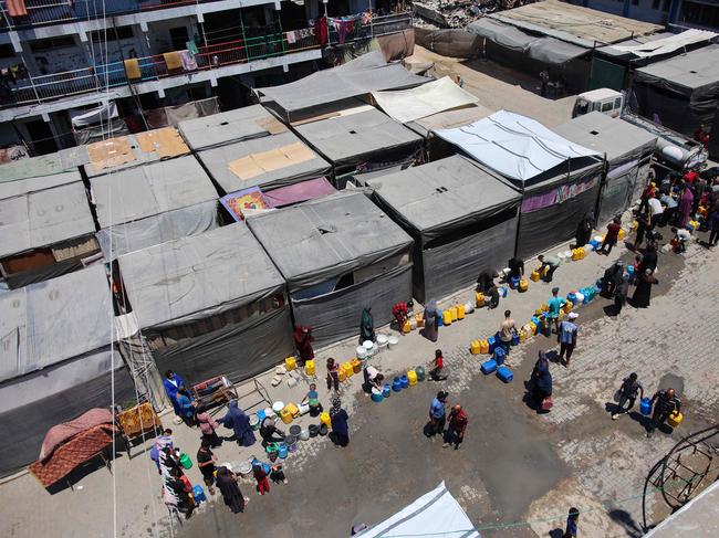 Displaced Palestinians line up to fill containers with water at a UN Relief and Works Agency for Palestine Refugees (UNRWA) school in the Jabalia camp for Palestinian refugees in the northern Gaza Strip on July 23, 2024, amid the ongoing conflict between Israel and the militant group Hamas. (Photo by Omar AL-QATTAA / AFP)