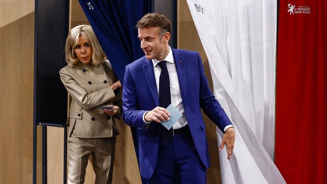 French President Emmanuel Macron and his wife Brigitte leave the voting booths after casting their votesat Le Touquet, northern France, on Sunday. Picture: AFP