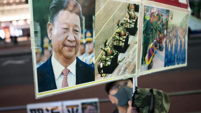 A protester holds a placard with a picture of Chinese President Xi Jinping during a rally commemorating victims of China's Covid Zero policy.