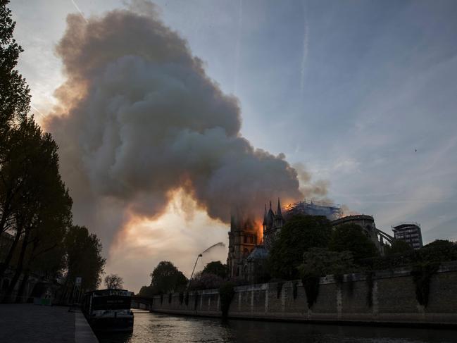 Flames and smoke are seen billowing from the roof at Notre-Dame Cathedral in Paris on April 15, 2019. - A huge fire swept through the roof of the famed Notre-Dame Cathedral in central Paris on April 15, 2019, sending flames and huge clouds of grey smoke billowing into the sky. The flames and smoke plumed from the spire and roof of the gothic cathedral, visited by millions of people a year. A spokesman for the cathedral told AFP that the wooden structure supporting the roof was being gutted by the blaze. (Photo by THOMAS SAMSON / AFP)