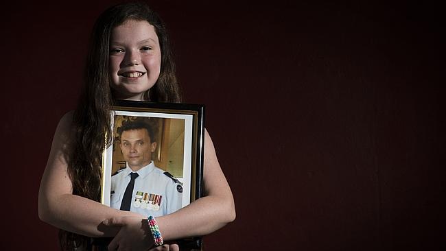 Madison Van Esveld, 11 holds a photo of her father Greg Van Esveld, 41, Royal Australian Air Force, who is currently stationed in Canberra / Picture: Chris McKeen