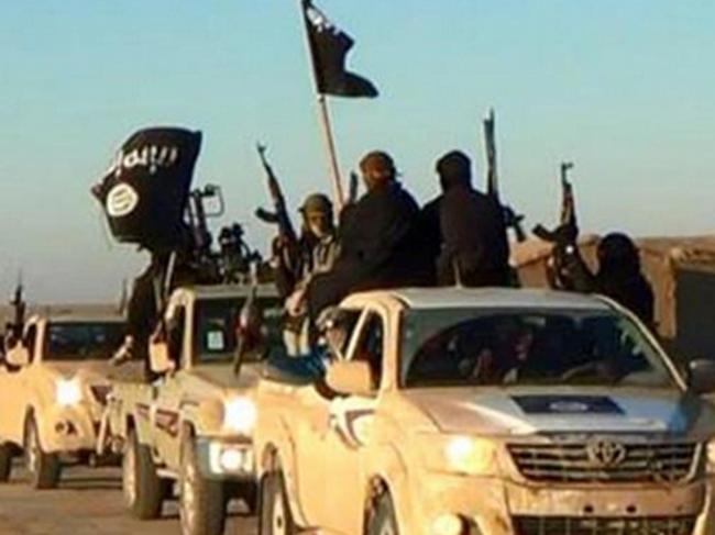 FILE - In this undated file photo released online in the summer of 2014 on a militant social media account, which has been verified and is consistent with other AP reporting, militants of the Islamic State group hold up their weapons and wave its flags on their vehicles in a convoy on a road leading to Iraq, in Raqqa, Syria. The extremist group that once bragged about minting its own currency is now accepting only U.S. dollars in Raqqa, slashing salaries across the board and imposing “exit fees” for those trying to leave its domain. (Militant photo via AP, File)