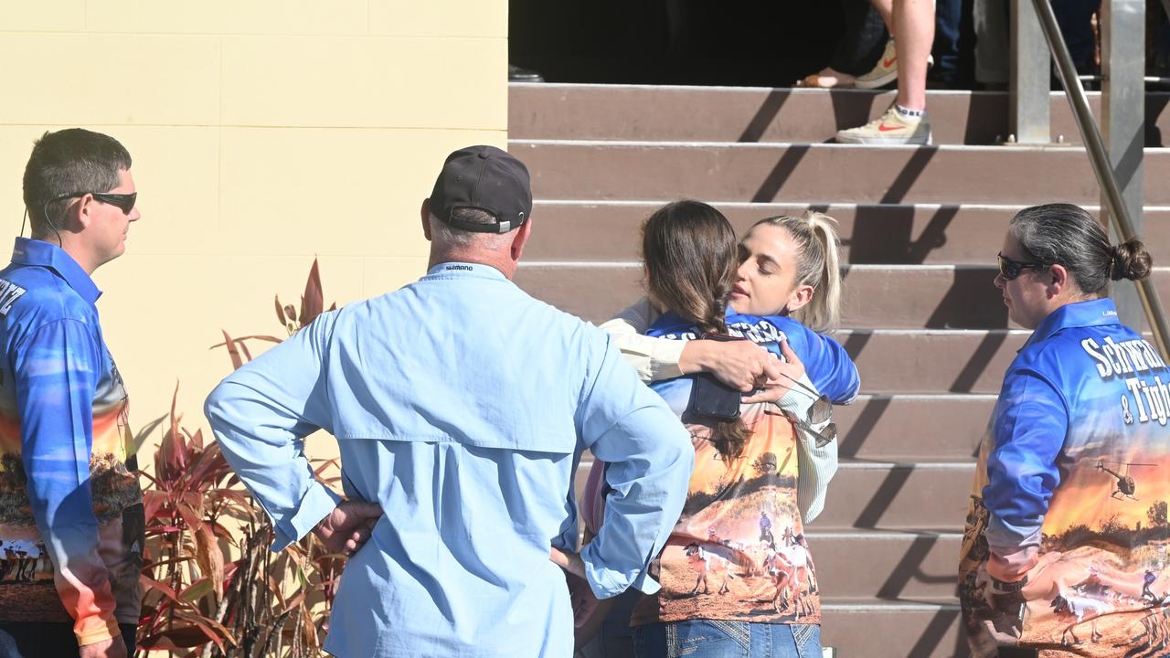 Friends and family surround the girlfriend of Ross Tighe, the sole survivor of the Bogie triple shooting, ahead of the committal hearing in Mackay for Darryl Valroy Young, who is accused of murdering Mervyn and Maree Schwarz and Graham Tighe.