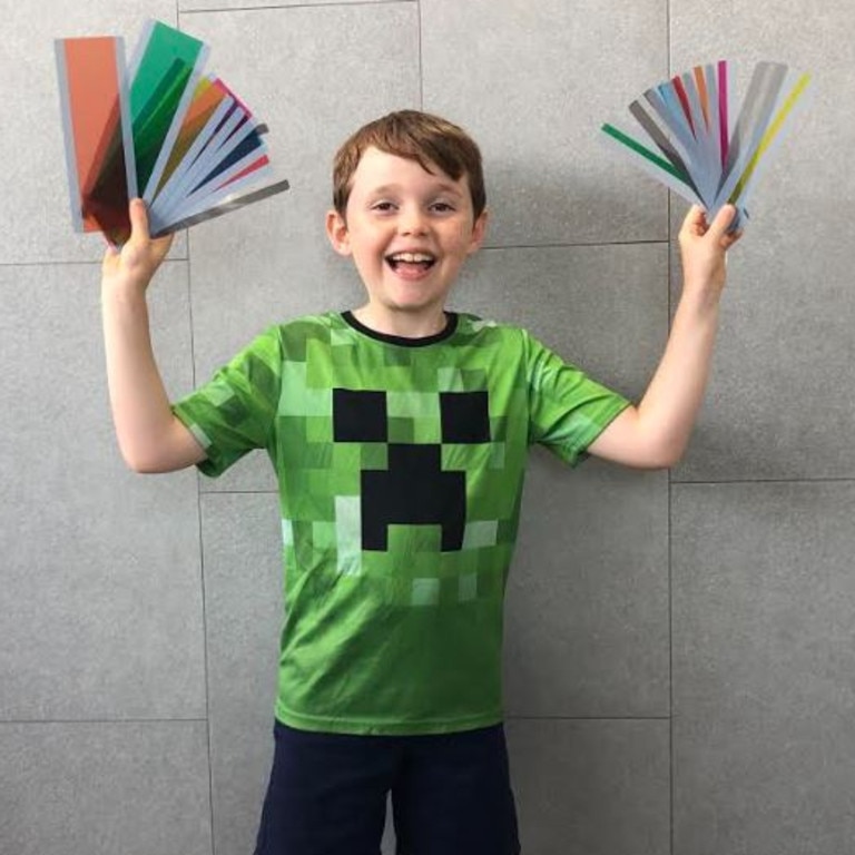 Levi holds a mega ruler pack in one hand and a mini ruler pack in the other. Each pack contains eight different coloured rulers so kids can work out which colour helps them most.