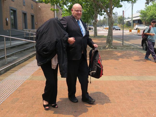 Lisa Curtale (covered) is escorted from Wyong Local Court by her solicitor Greg Schumer. Picture: Richard Noone