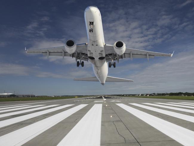 Plane taking off at the end of the runway with outstretched landing gear