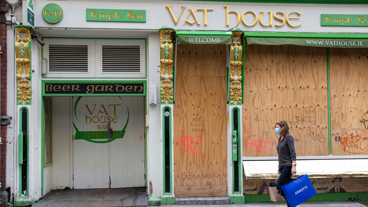 A woman walks past a boarded up bar in Dublin. Picture: Paul Faith/AFP