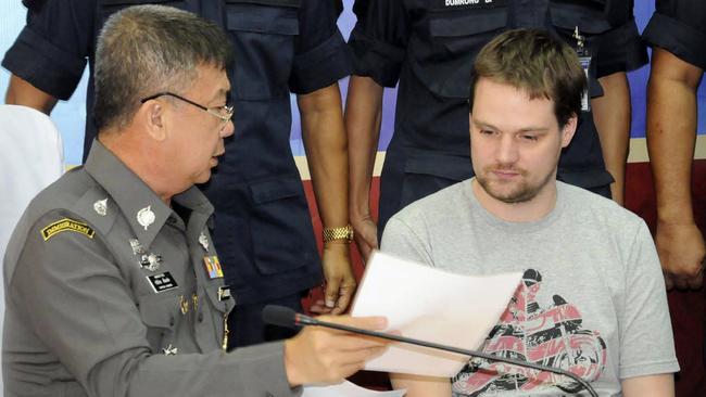 A Thai immigration officer, left, shows a paper document to Swedish Hans Fredrik Lennart Neij at Immigration office in Nong Khai province, Thailand, Tuesday, Nov. 4, 2014. Neij, one of the founders of popular file-sharing website The Pirate Bay, has been arrested under an Interpol warrant as he was crossing into Thailand from Laos, police said Tuesday. (AP Photo) THAILAND OUT