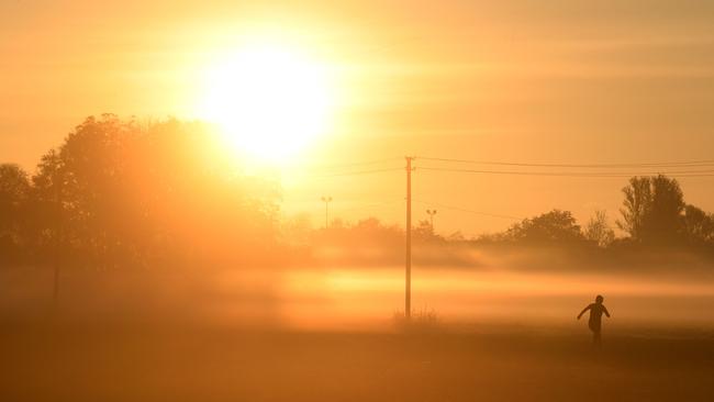 A jogger runs through the fog as sun rises in the village of Puchheim, southern Germany. Picture: AFP