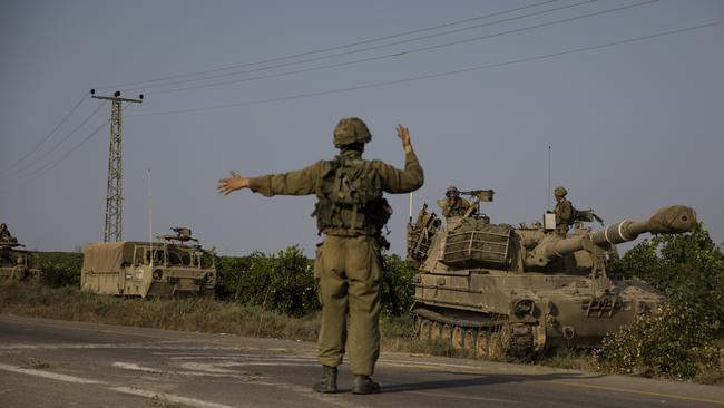 An Israeli soldier directs armoured vehicles heading towards the southern border with the Gaza Strip on Sunday. Picture: Getty Images