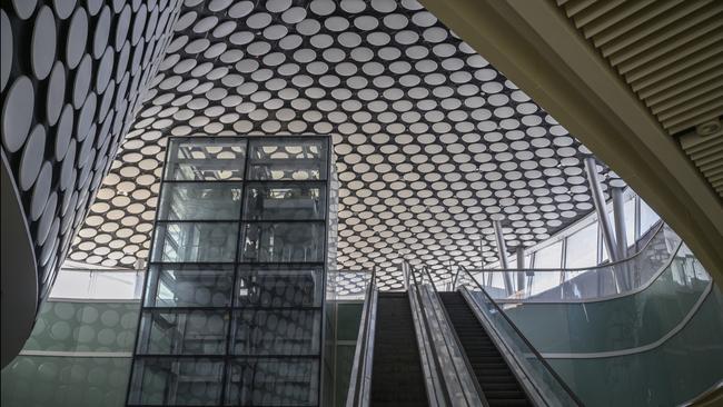 A foreign journalist walks down an escalator in the plaza at the Beijing Winter Olympic Village. Picture: Getty