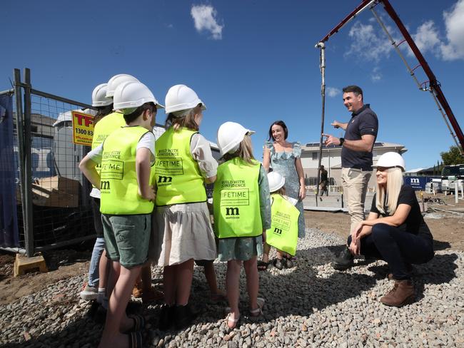 The Wilkinson children listen on as Greg Heaton from Metricon, along with Danielle Carroll (left) and organizer Tamika Smith, explains what builders are doing during the construction of their new house. Picture: Glenn Hampson.