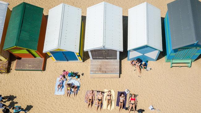 People sun bake at the Brighton Beach Boxes. Picture: Jake Nowakowski