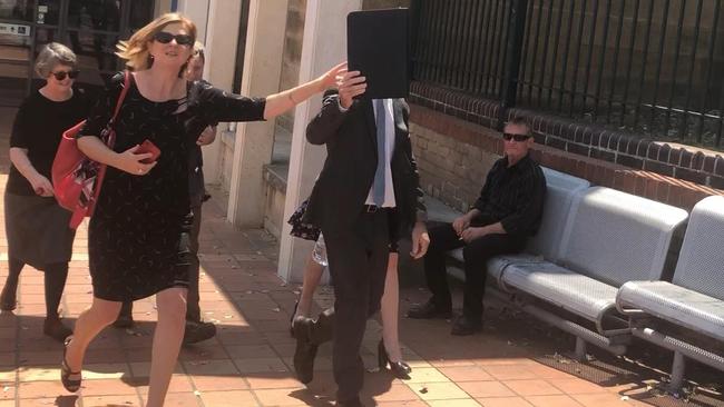 A camera-shy Neile Robinson leaves Campbelltown Court with his wife and supporters.