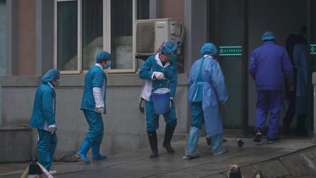 Workers clean the emergency entrance of a Wuhan clinic. Picture: AP