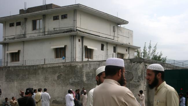 Residents and reporters stand outside the house where al-Qaida Leader Osama Bin Laden was caught and killed by US forces in Abbottabad, Pakistan in 2011.