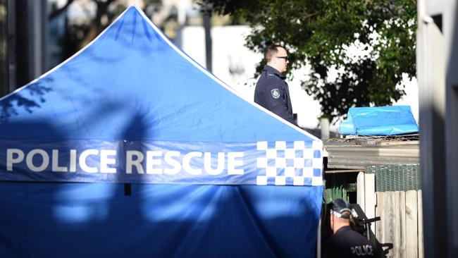 Police officers oversee the placing of the tarpaulin on the garage roof. Picture: Darren Leigh Roberts