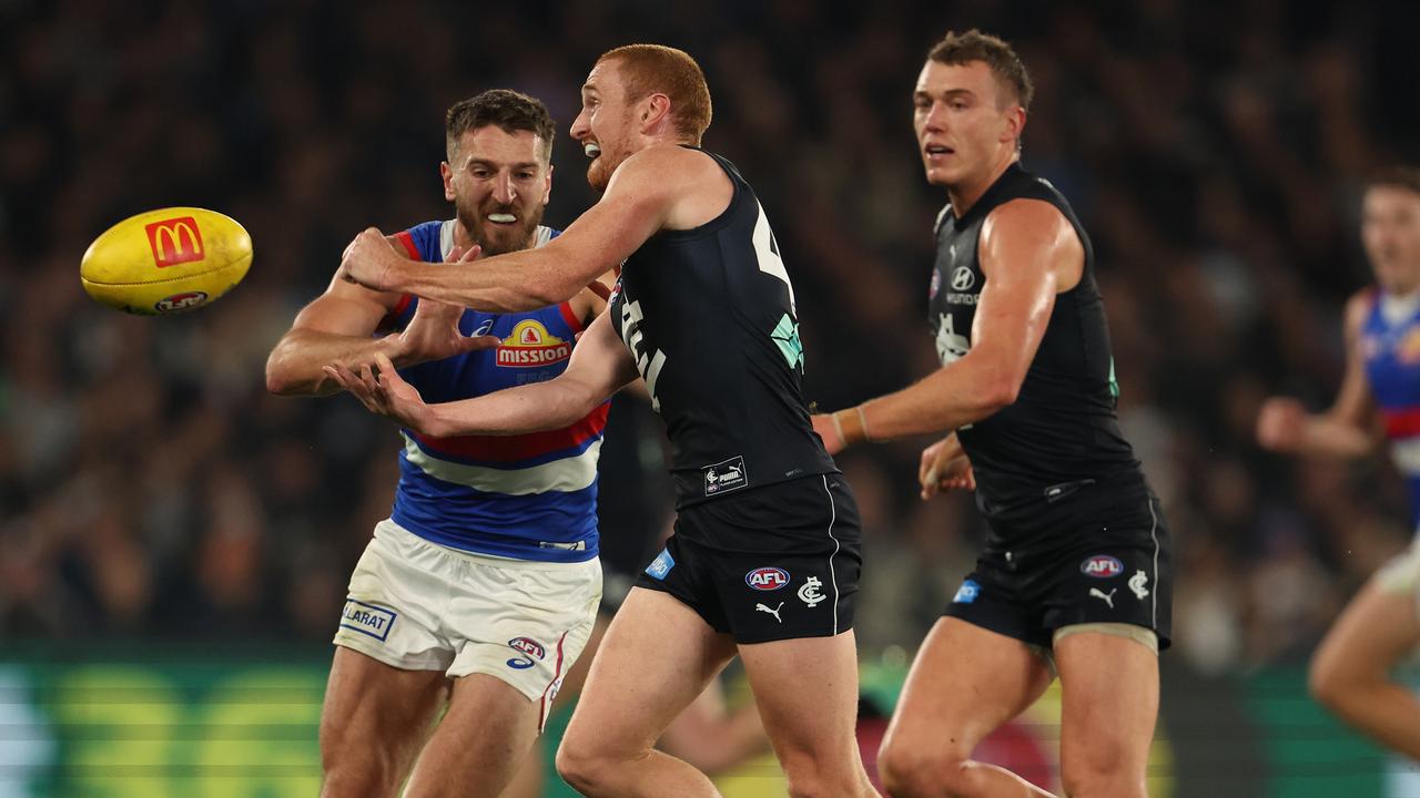 Matt Cottrell handballs as Marcus Bontempelli closes in.