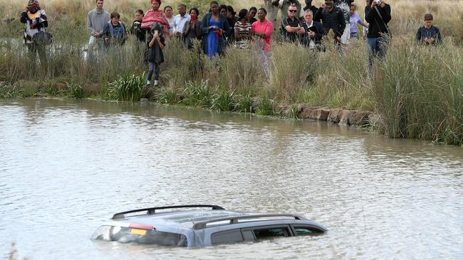 A group watches on as police divers prepare to remove Akon Guode's car from the lake. Picture: Mark Stewart