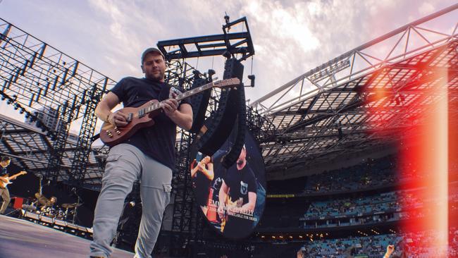 Josh Simons plays guitar with Emmanuel kelly as the opening act for Coldplay in 2024.