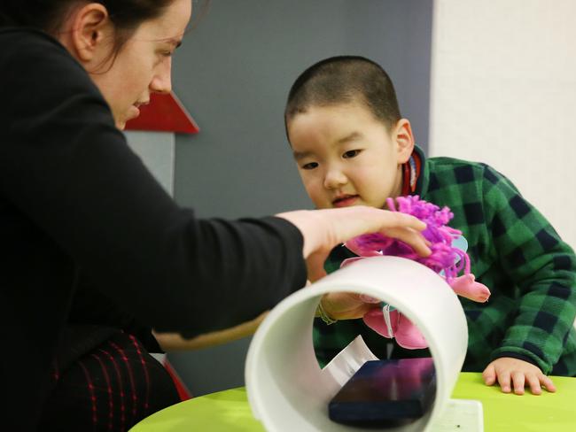 Charles gets introduced to a toy MRI machine with the help of Marilena DeMayo. Visual instruction and demonstration can be very helpful for people with autism. Picture: Toby Zerna