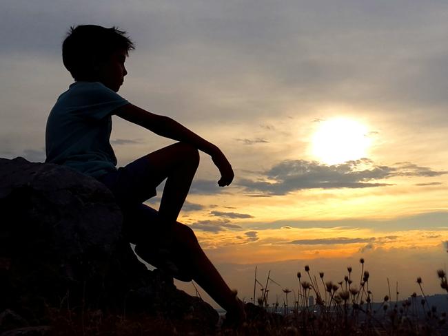 Relaxed boy on hill.