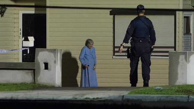 A police officer speaks to a local disturbed by the floodlights at the Bankstown crime scene. Picture: Chris McKeen