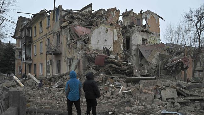 Residents stand among debris of a residential building partially destroyed by a missile attack in the town of Selydove, Donetsk region, on February 8. Nearly one in four Australians believes the government should do more to help Ukraine. Picture: Genya Savilov/AFP