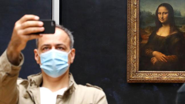 A visitor to the Louvre takes a selfie in front of the Mona Lisa. Picture: Getty Images.