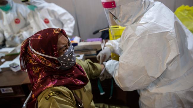 An Indonesian medic takes a blood sample from a woman during a rapid test in Surabaya. Picture: AFP