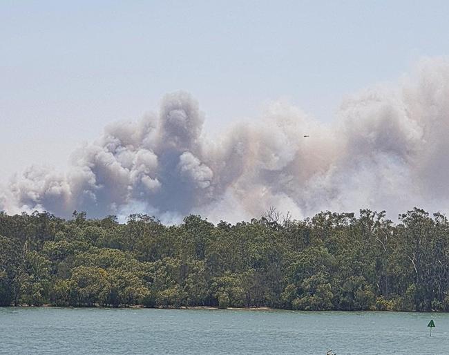 FIRE: Smoke billows from Noosa as aircrafts begin their water bombing run.