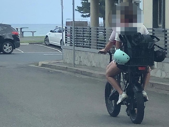 Two teenagers, with their helmets dangling, on an e-bike near Queenscliff Beach. Picture: Jim O'Rourke