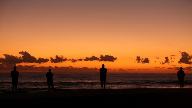 GOLD COAST, AUSTRALIA - APRIL 25: People watch the sunrise on Currumbin Beach to commemorate Anzac Day on April 25, 2020 in Gold Coast, Australia. Traditional Anzac Day ceremonies have been cancelled due to the global COVID-19 pandemic and subsequent restrictions on gatherings of people. Anzac day is a national holiday in Australia, traditionally marked by a dawn service held during the time of the original Gallipoli landing and commemorated with ceremonies and parades throughout the day, however with social distancing measures in place because of coronavirus (COVID-19), Australians this year are observing the day differently. Anzac Day commemorates the day the Australian and New Zealand Army Corp (ANZAC) landed on the shores of Gallipoli on April 25, 1915, during World War 1. (Photo by Chris Hyde/Getty Images)