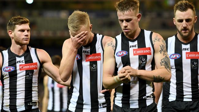 Dejected Magpies walk off the MCG.