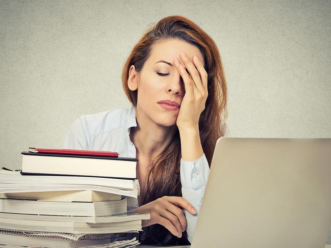 Too much work tired sleepy young woman sitting at her desk with books in front of laptop computer isolated grey wall office background. Busy schedule in college, workplace, sleep deprivation concept