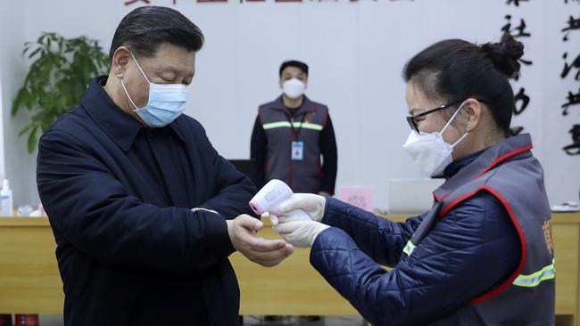 Chinese President Xi Jinping, left, wearing a protective face mask, receives a temperature check at a community health center in Beijing. Picture: Pang Xinglei/Xinhua via AP