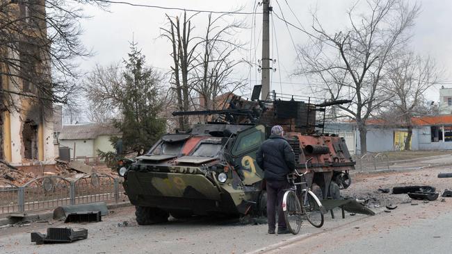 A man looks at an Ukrainian armored personnel carrier (APC) BTR-4 destroyed as a result of fight not far from the centre of the Ukrainian city of Kharkiv.