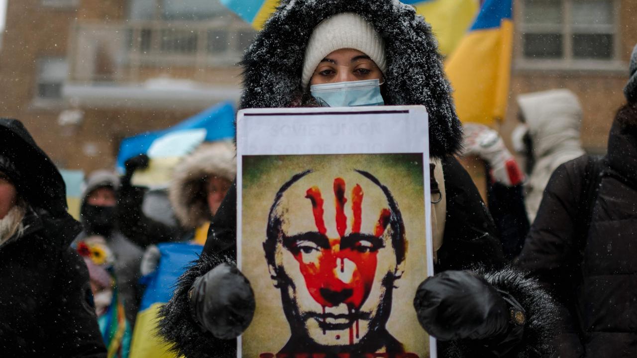 There is growing condemnation of Putin. In Quebec, a woman holds a portrait of Putin with a bloody hand on his face as members of the Ukrainian community protest. Picture: Andrej Ivanov/AFP