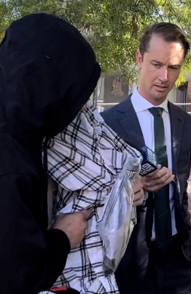 Nathan Bernhard [pictured under checkered blanket] leaving Nowra Police Station with his brother [pictured in black hoodie]. Picture: Tom McGann.