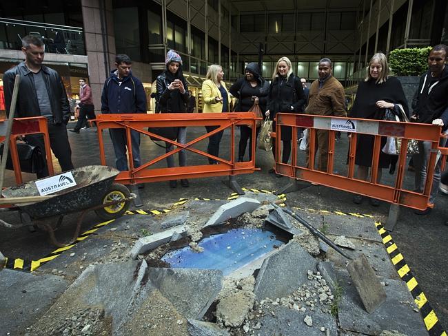 Looks tempting ... Londoners examine a “sinkhole” installation that purports to give them a glimpse at Bondi and the Gold Coast in a new stunt to promote Australian tourism. Picture: Ella Pellegrini