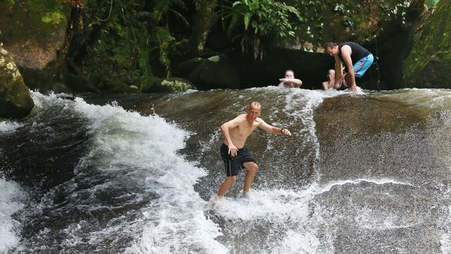 Police are warning both tourists and locals to take care while swimming in creeks and streams this wet season. Conditions can change quickly and submerged and slippery rocks can prove deadly. Andrew Huxham slides down Josephine Falls on his feet. Picture: BRENDAN RADKE.