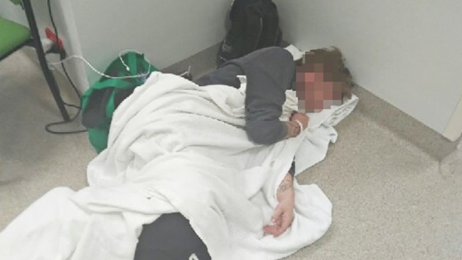 A patient waiting for treatment at the Royal Hobart Hospital makes a bed on the floor.