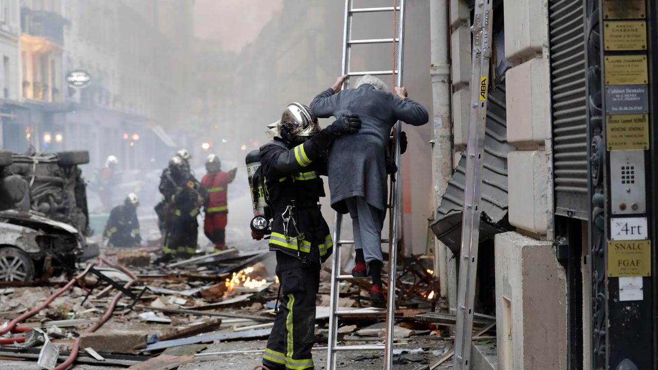 A woman is evacuated by firefighters after the explosion. Picture: AFP 