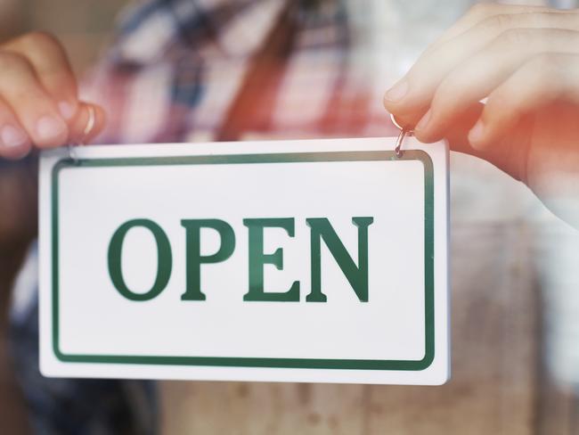 Close up shot of person holding an 'OPEN' sign against the class of the cafe door. Free to use from iStock