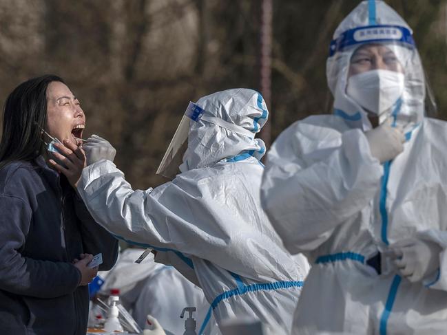 A health worker wears protective gear as she gives a nucleic acid test to detect COVID-19 on a local resident at a mass testing site after new cases were found, on April 6, 2022 in Beijing, China. Picture: Frayer/Getty Images.